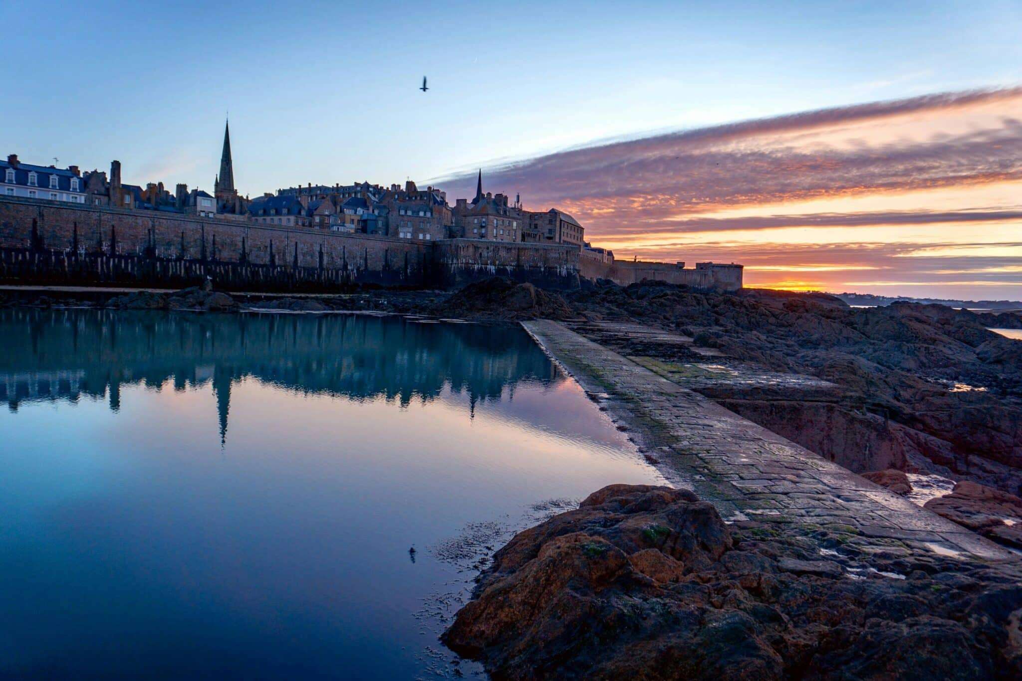 Remparts de Saint-Malo reflétés dans l'eau calme au lever du soleil