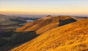 Collines herbeuses dorées au coucher du soleil en Auvergne